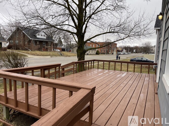 A wooden deck with a railing and a tree in the background.