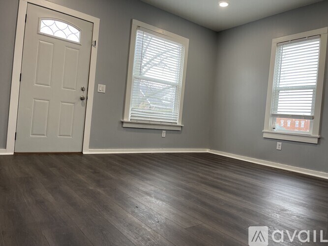 A room with a white door and two windows with blinds.