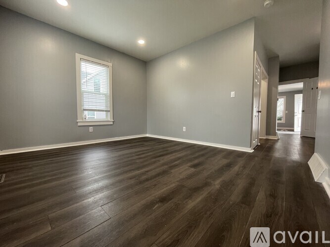 A room with wooden flooring and a window with blinds.