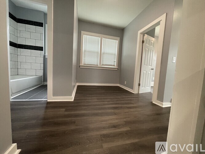 A room with wooden floors and a window with blinds.