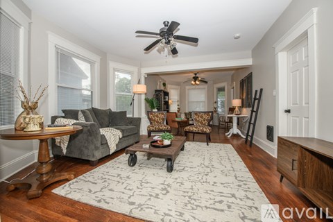 A living room with a grey couch, a coffee table, and a rug with a pattern.