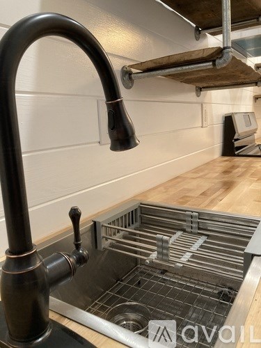 A kitchen sink with a black faucet and a metal grate.