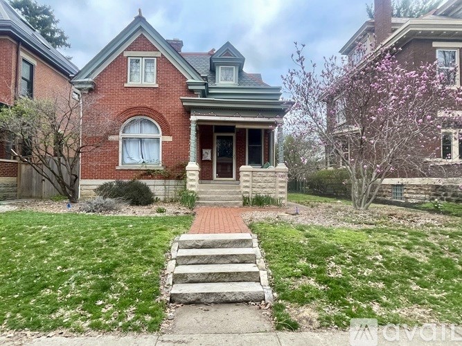 A red brick house with a green roof and a front porch.