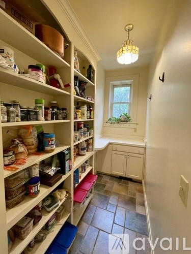 A long hallway with shelves on the side and a window in the middle.