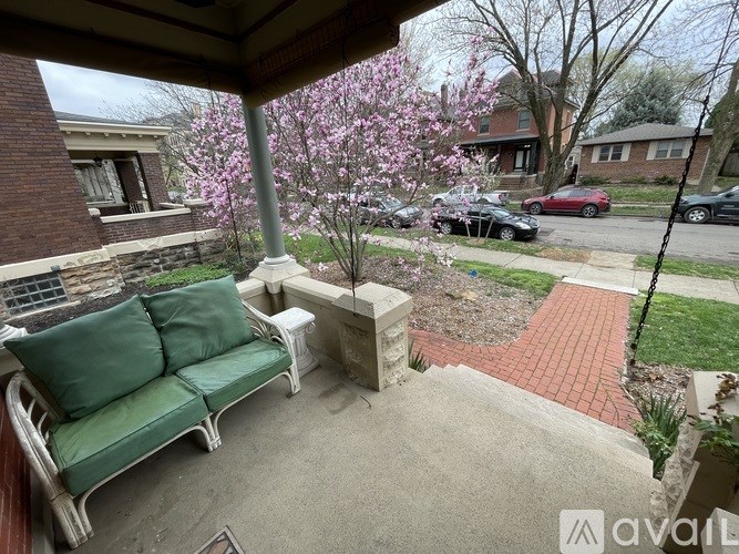 A patio with a green couch and a tree with pink flowers.