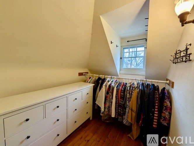 A room with a white wall and a row of clothes hanging up.