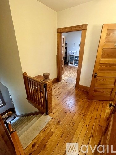 A wooden staircase with a carpeted runner leads to another room.
