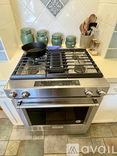 A modern stainless steel stove with a black pan on the burner.