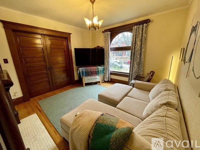 A living room with a couch, a rug, and a chandelier.