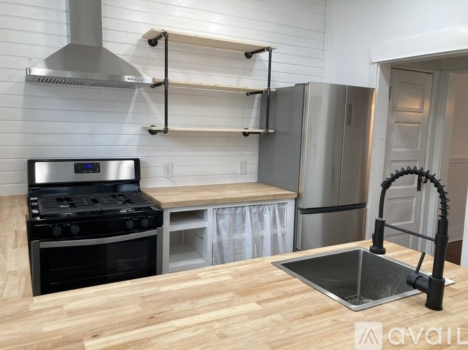 A kitchen with a stove, sink, and refrigerator.