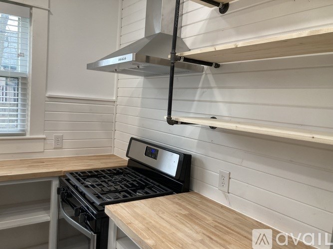 A kitchen with a stove top oven and a range hood above it.