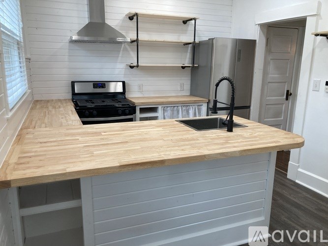 A kitchen with a wooden countertop and a black stove top oven.