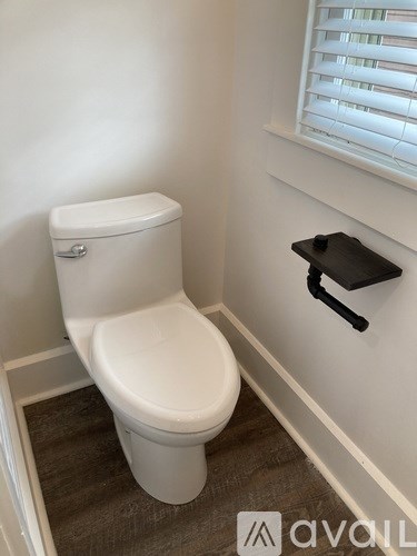 A white toilet in a small bathroom with a black towel bar on the wall.