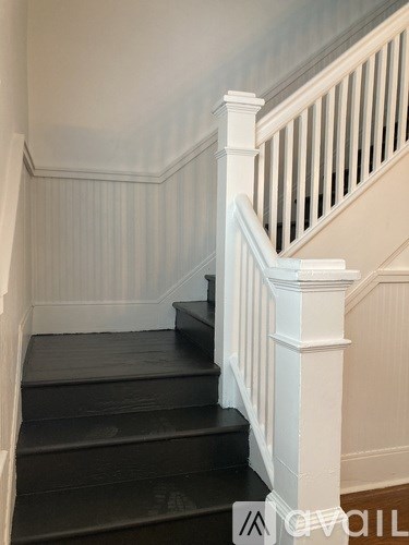 A staircase with white railings and black steps.