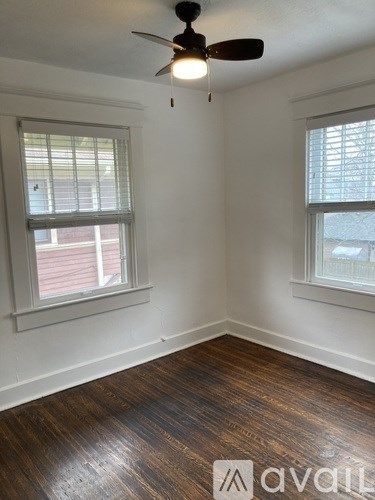 A room with wooden floors and two windows.
