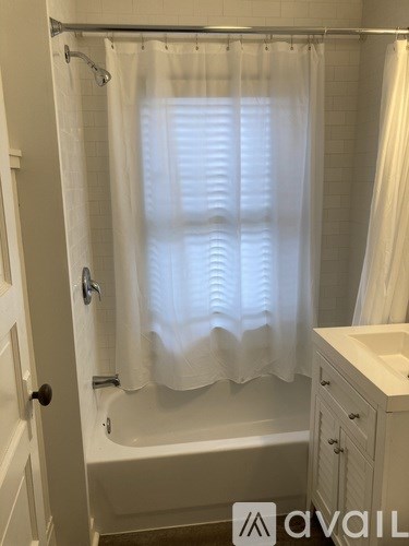A white shower curtain is hanging in a bathroom.