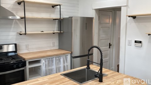 A kitchen with a stove top oven, a sink, and a refrigerator.