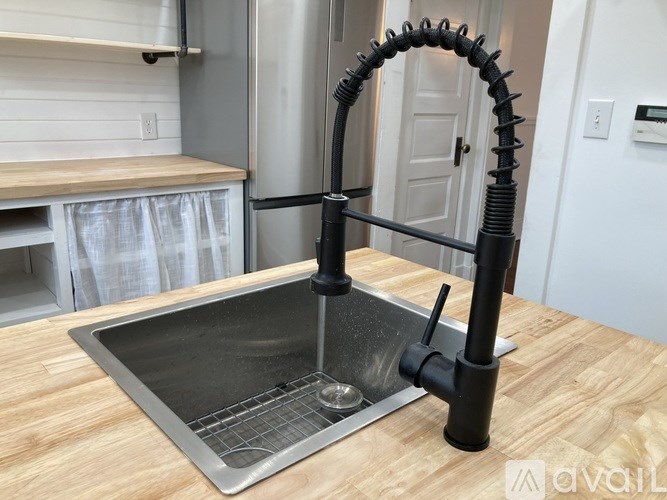 A kitchen sink with a black pipe attached to it.