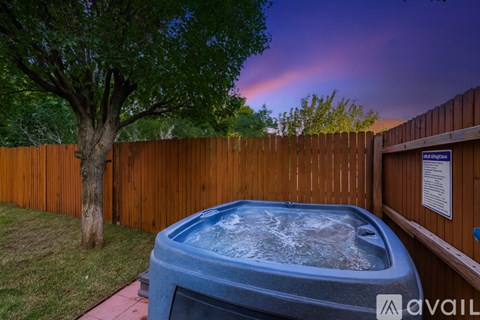 A hot tub sits in a backyard surrounded by a wooden fence.