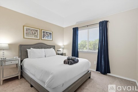 A bedroom with a large bed and a window with blue curtains.
