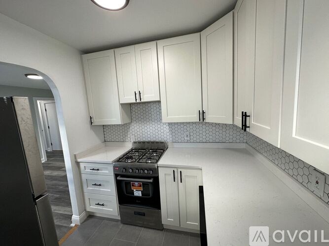 A kitchen with white cabinets and a black stove top oven.
