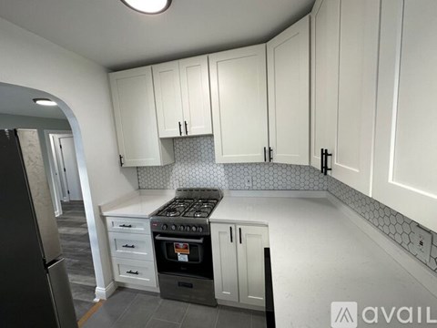 A kitchen with white cabinets and a black stove top oven.