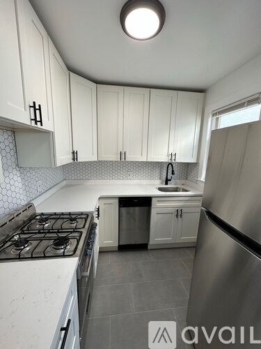 A kitchen with white cabinets and a stainless steel refrigerator.