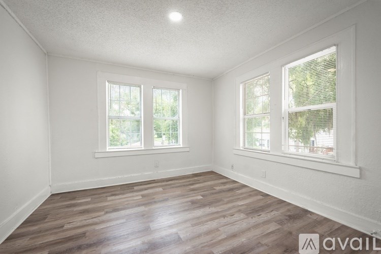 A room with wooden floors and three windows.