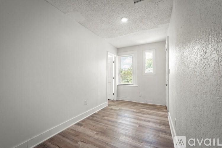 A room with wooden flooring and a door leading to a balcony.