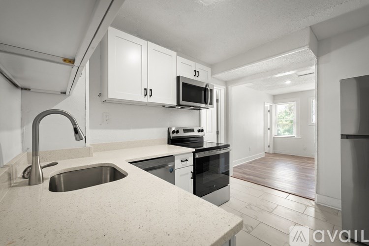 A kitchen with a sink, stove, and cabinets.