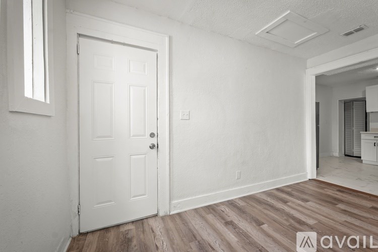 A white door is in a room with wooden floors and white walls.