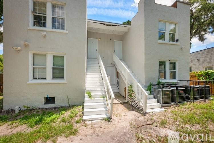 A two-story house with a white exterior and a staircase leading to the front door.