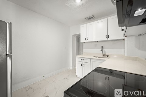 A kitchen with white cabinets and a black fridge.