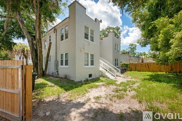 A white two-story house with a wooden fence in front.
