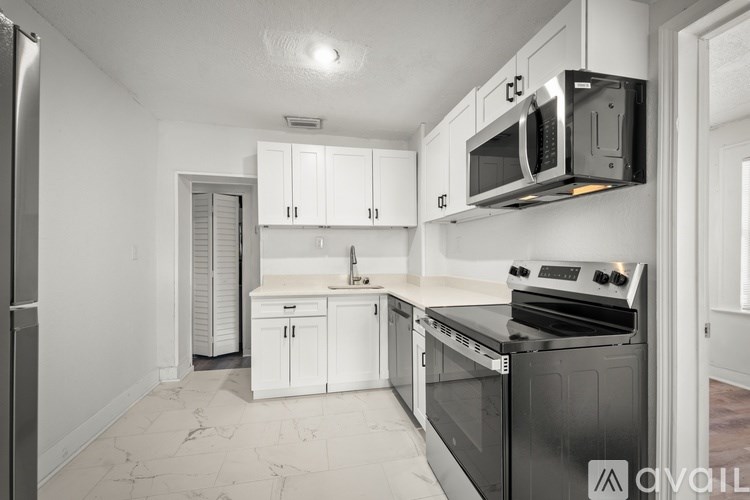 A kitchen with white cabinets and black appliances.