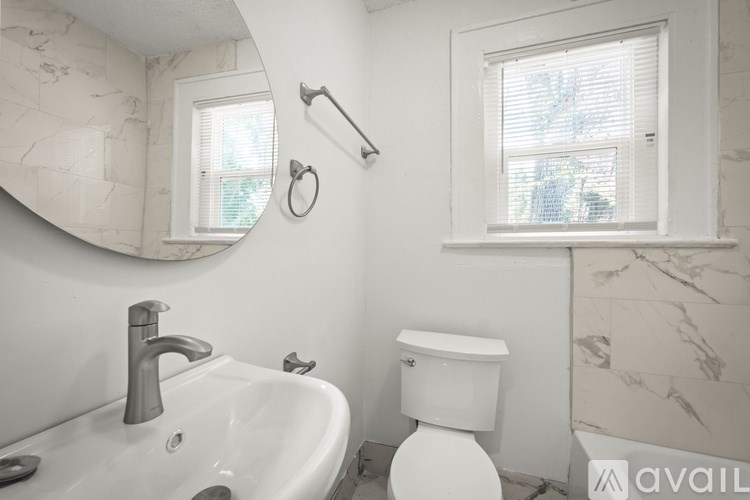 A bathroom with a white toilet, sink, and a window.