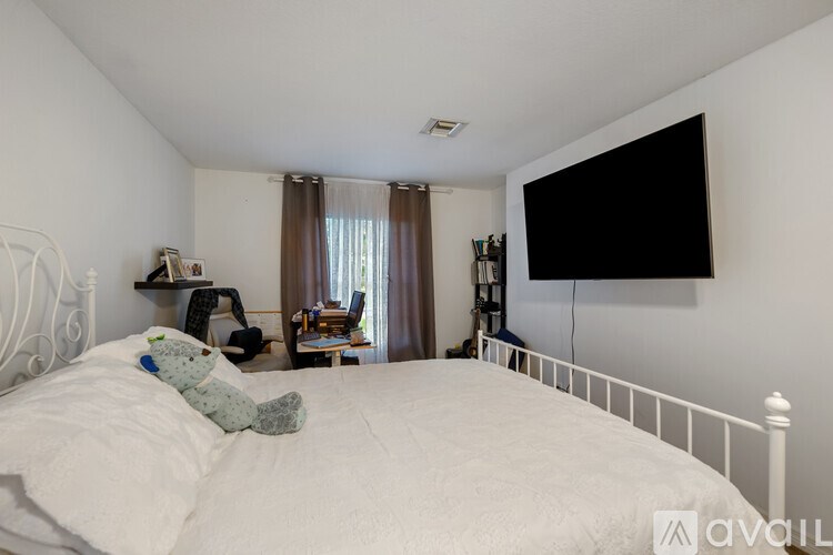 A white bed with a white headboard and a white bedspread with a blue teddy bear on it.