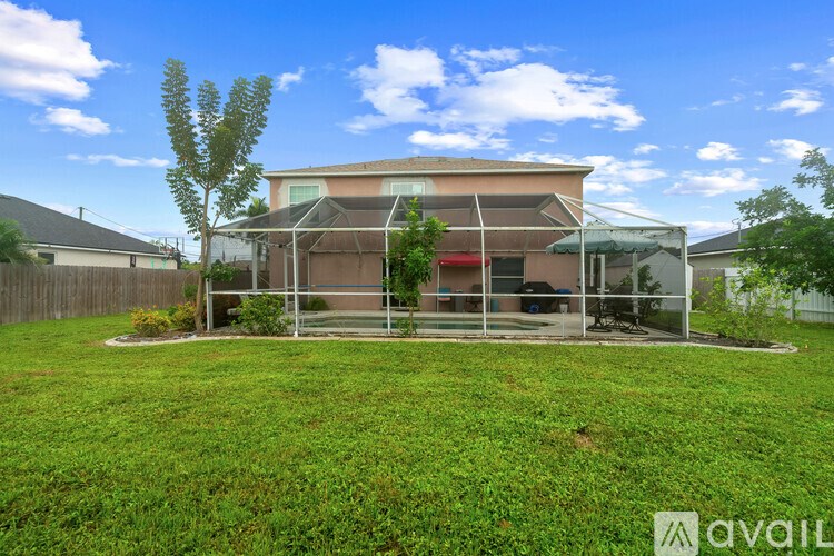A house with a fenced backyard and a tree.