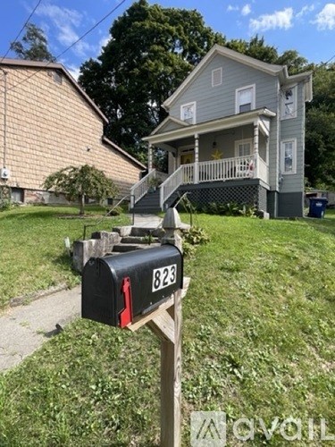 A mailbox with the number 823 on it is in front of a house.