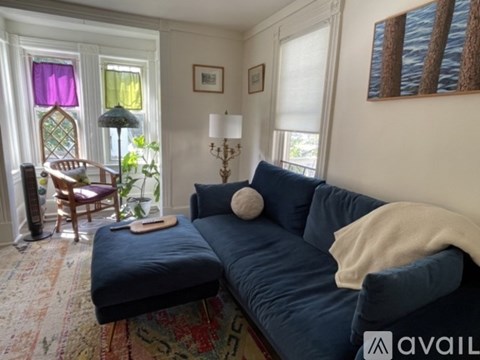 A living room with a blue couch and a wooden chair.