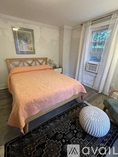 A bedroom with a bed, a rug, and a picture on the wall.
