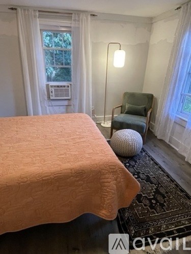 A bedroom with a bed, chair, and window.