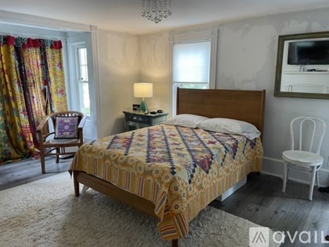 A bedroom with a large bed and a chair.