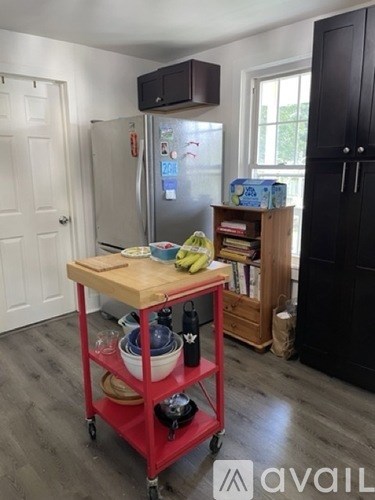 A kitchen with a red cart and a black fridge.