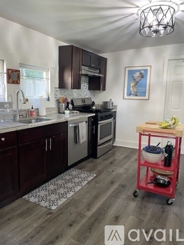 A kitchen with a red cart holding cooking utensils.