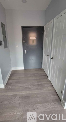 A hallway with a grey door and a white door on the right.