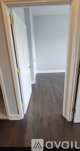 A room with a white door and a wooden floor.