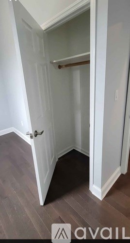 A small white closet with a door and a shelf.