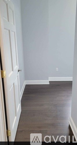 A hallway with a wooden floor and white walls.