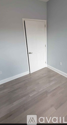 A room with a white door and wooden flooring.